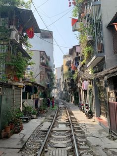 an old train track running through a narrow alleyway with buildings on both sides and people walking along the tracks