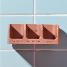 a pink soap dispenser on a blue tile wall with the words shampoo conditioner and body