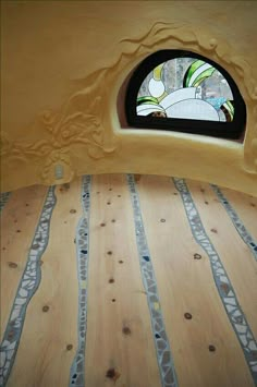 a window in the side of a building with wood flooring and decorative designs on it