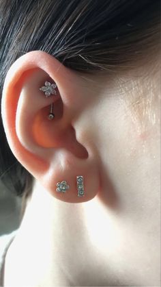 an ear with three piercings attached to it's sides and two smaller ones behind the ear