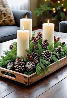 a tray with candles and pine cones in it sitting on a wooden table next to a couch