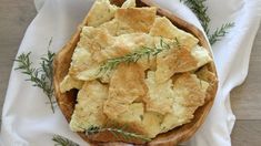 a wooden bowl filled with crackers on top of a white cloth next to a napkin