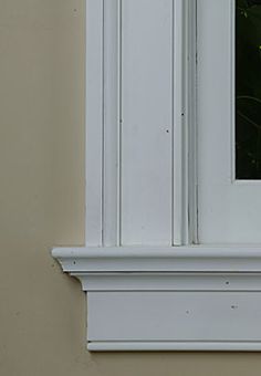 a cat sitting on the ledge of a window sill