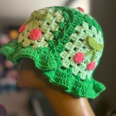 a crocheted green hat with pink flowers on it