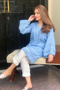 a woman sitting on top of a bench in front of a door with her legs crossed