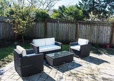 an outdoor patio area with wicker furniture and brick pavers flooring, along with a wooden fence