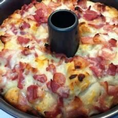 a pizza with ham and cheese in a pan on top of stove burners, ready to be cooked