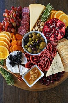 a wooden platter filled with different types of cheeses and fruit on top of it