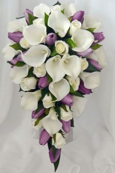 a bridal bouquet with white and purple flowers on it's side, in front of a white background