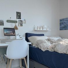 a bed sitting next to a desk with a computer on top of it in a bedroom