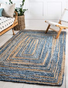 a living room area with two chairs and a rug on the floor in front of a couch