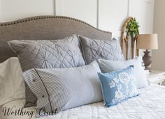 a bed with blue and white pillows on top of it