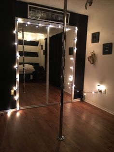 a mirror with some lights on it in a room that has wood floors and black walls