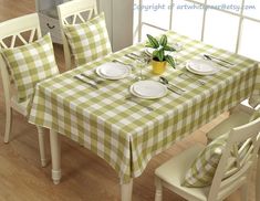 a dining room table with green and white checkered cloth on it, set for four