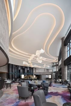 a large lobby with chairs, tables and lamps on the ceiling is lit by lights that look like swirls