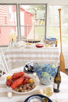 the table is set with food and drinks for two people to enjoy in front of the window