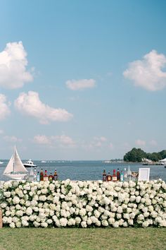 a table with white flowers on it in front of the water