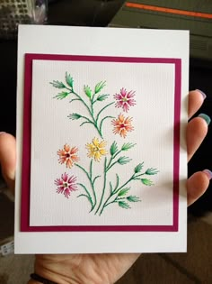 a hand holding a card with flowers painted on it