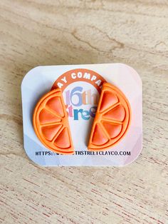 an orange slice shaped brooch sitting on top of a piece of paper with the words my company