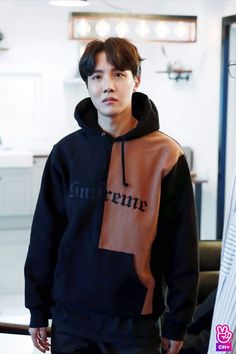 a young man wearing a black and brown hoodie with the word supreme on it