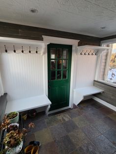 a green door sitting next to a white bench in a room filled with potted plants