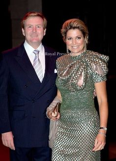 a man and woman standing next to each other in front of a red carpeted floor