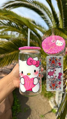 hello kitty tumbler cup with pink lid and straw in front of palm tree,