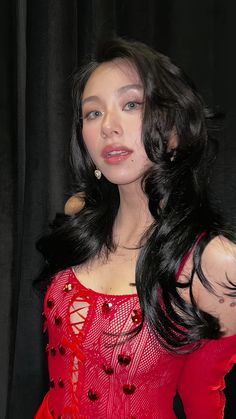 a woman with long black hair wearing a red dress