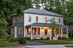 a large white house sitting next to a lush green forest