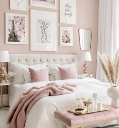 a bedroom with pink walls and pictures on the wall above the bed, along with white linens