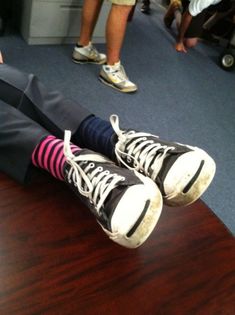 a pair of feet with socks on sitting on top of a wooden table in an office