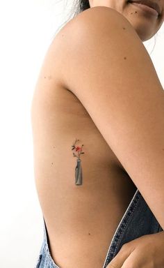 a woman with a flower tattoo on her left arm and shoulder, holding onto a pair of jeans