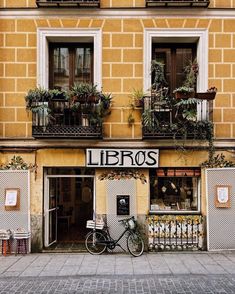 a bike is parked in front of a building with plants on the windows and balconies