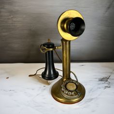 an old fashioned phone is sitting on a marble counter top with a black and gold cord