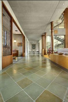 a long hallway with wooden columns and tile flooring on both sides, leading up to the second floor