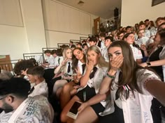 a group of people sitting next to each other in front of a crowd with their hands covering their mouths