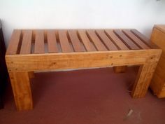 a wooden bench sitting on top of a red floor next to a dresser and table