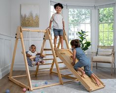 three children playing on a wooden swing set in a living room with white walls and hardwood floors