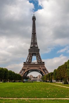 the eiffel tower is surrounded by trees and grass in front of a cloudy sky