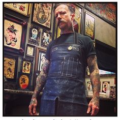 a man with tattoos wearing an apron and holding a knife