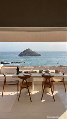 the dining table is set for two with an ocean view in the backround