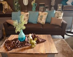 a living room filled with furniture and pillows on top of a wooden table in front of a brown couch