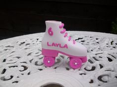 a pink roller skate sitting on top of a white lace covered tablecloth with the word lavya written on it