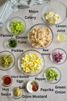 the ingredients for this meal are displayed in bowls on a table top, including onions, celery, parsley, mayo