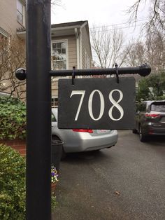 a black and white house number sign in front of a car parked on the street