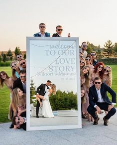 a group of people posing in front of a welcome to our love story photo sign