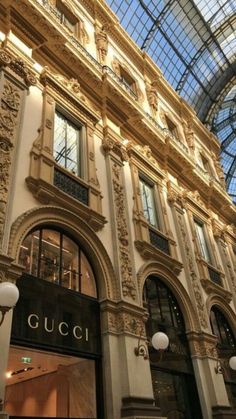 the inside of a building with many windows and lights on it's sides, in front of a glass ceiling