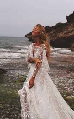 a woman in a white dress standing on the beach