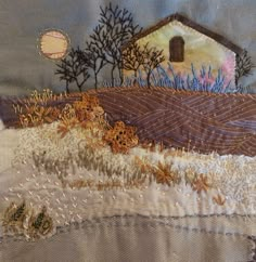 a patchwork quilt with a house and trees on the hill next to it,