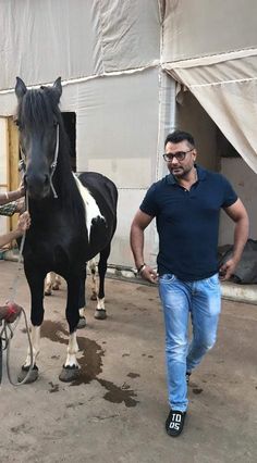 a man leading a black and white horse